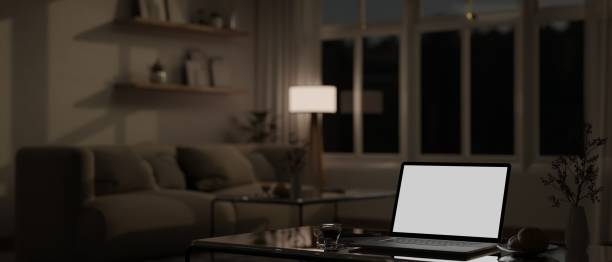 istock Workspace with laptop white screen mockup on a coffee table in a living room at night. 1485042553