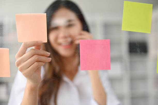 istock A young Asian female office worker talking on the phone and reading sticky notes 1485043079