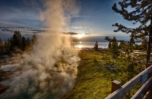 A spectacular view of a geyser erupting in Yellowstone National Park during the magical hour of sunrise