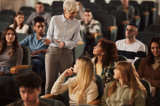 istock Happy senior female professor talking to her students on a class at lecture hall. 1485045570
