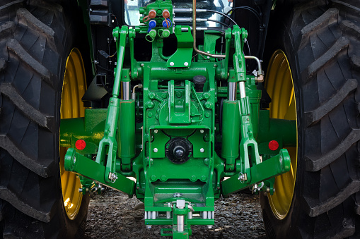 Rear view of a modern industrial tractor painted in green. Mechanisms and control units for additional equipment.