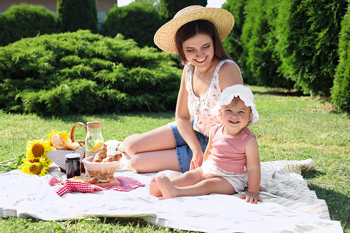 Mother and her daughter having picnic in garden on sunny day
