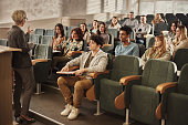College students listening to their senior teacher on a class at lecture hall.