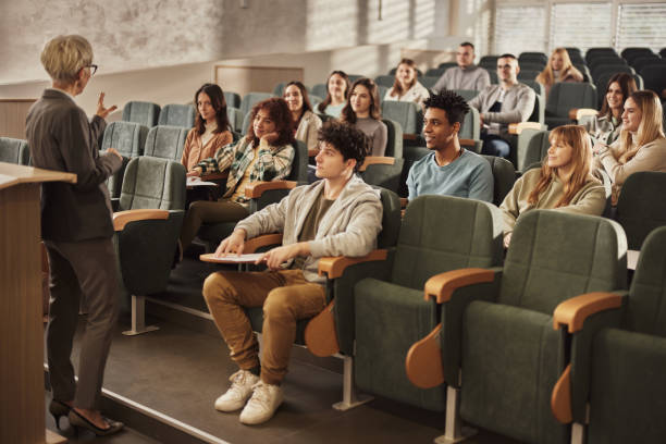 College students listening to their senior teacher on a class at lecture hall. stock photo