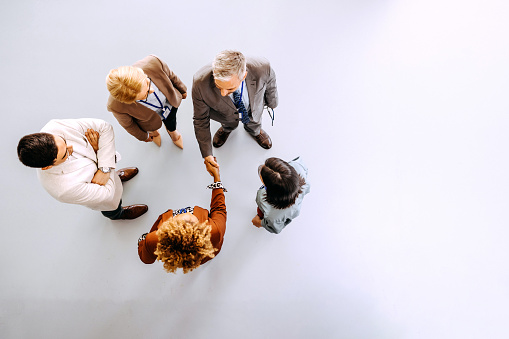 High angle view studio shot of business partners shaking hands in the office hallway