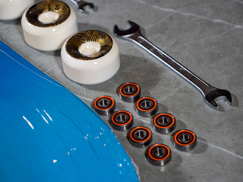 LA, UNITED STATES, APRIL 2022: CLOSE UP: Lined up set of skateboarding wheels and bearings ready for assembly. Brand new skateboard parts on workshop countertop prepared for mounting on skateboard.