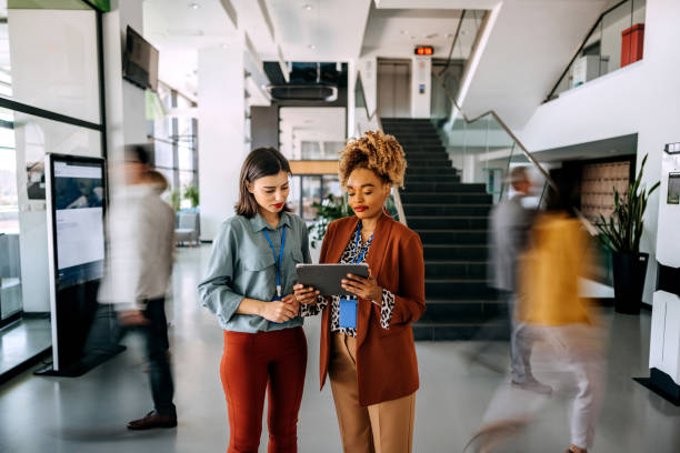 istock Female coworkers discussing work with people in blurred motion behind them 1485050345