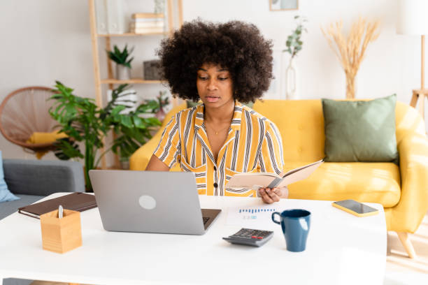 istock Smiling black woman using laptop at home 1485050402
