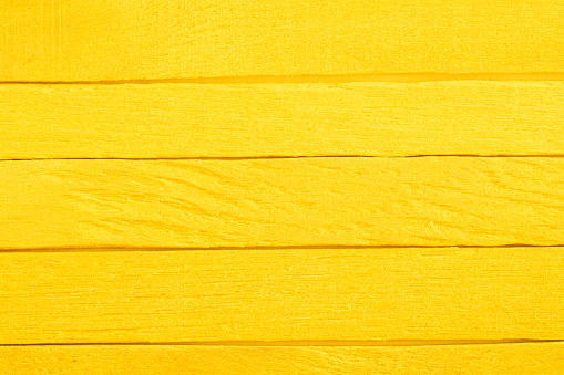 Old yellow wooden background. Yellow planks. Wooden textured background. Wooden painted yellow boards are located  horizontal in a row.