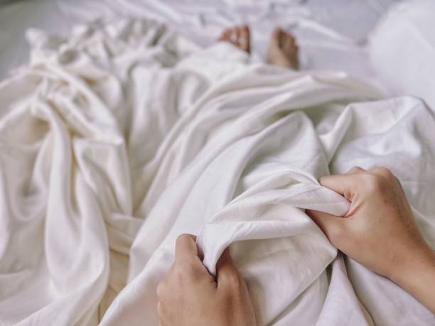 istock Cropped view of two hands holding on a rumpled bedspread 1485053019