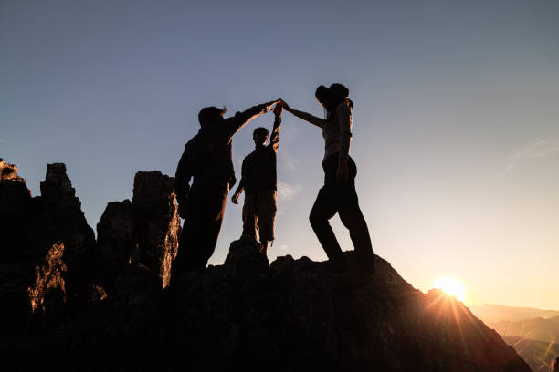 Silhouette of  happy teamwork hold hands up as a business successful, business victory, achieve business goal, Teamwork helping hand trust assistance. Silhouette of  happy teamwork hold hands up as a business successful, business victory, achieve business goal, Teamwork helping hand trust assistance. summit meeting stock pictures, royalty-free photos & images