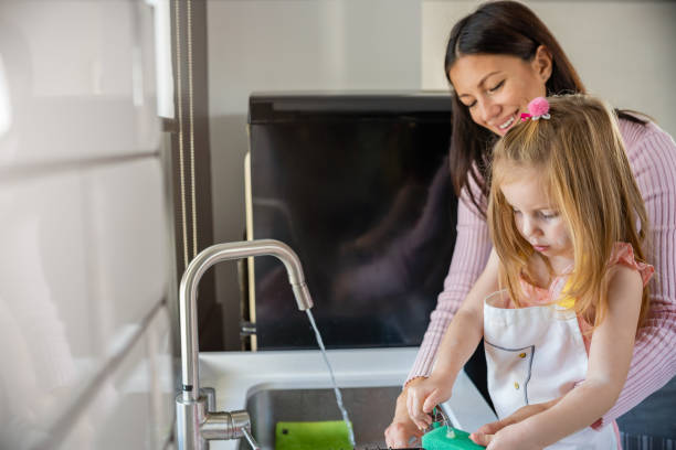 istock Child helping mother in the kitchen, washing dishes 1485064564