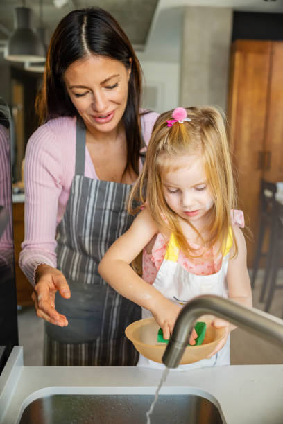 istock Child helping mother in the kitchen, washing dishes 1485068487