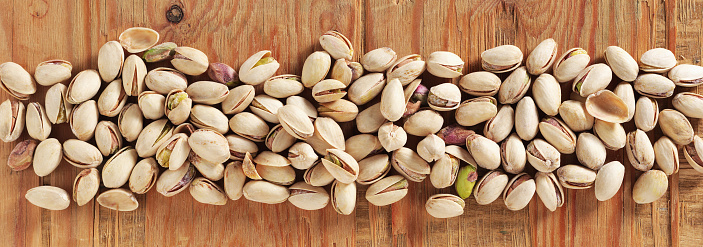 Roasted salted pistachios in shell on a wooden background, top view
