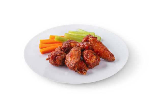 istock Fried chicken wings with celery and carrots in a plate on a board on a white background 1485071060