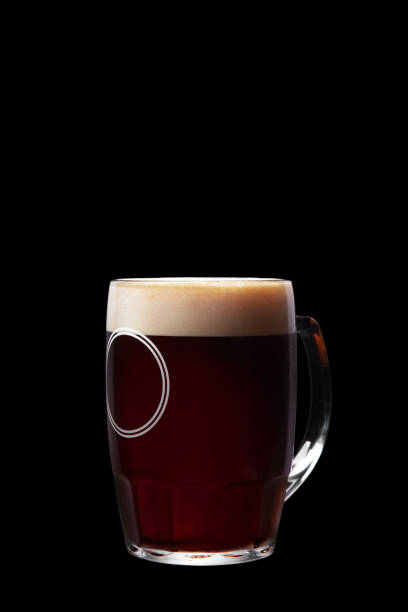 birra scura in un bicchiere su uno sfondo nero - bitter beer bottle alcohol beer foto e immagini stock