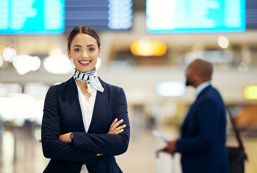 Woman, airport and service agent with arms crossed standing ready with smile in FAQ, help or direction. Portrait of happy female airline passenger assistant smiling for immigration or travel services