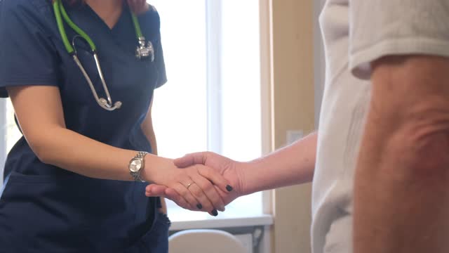 The doctor shakes hands with the patient. Positive interaction between doctor and patient