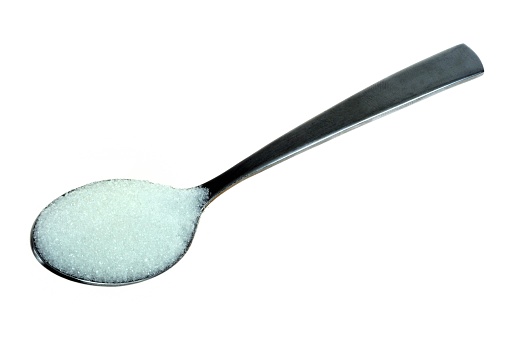 Spoon of powdered sugar close-up on white background