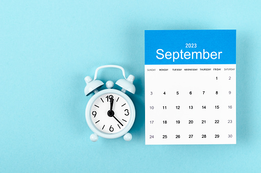 September 2023 Monthly calendar for 2023 year with vintage alarm clock on blue background.