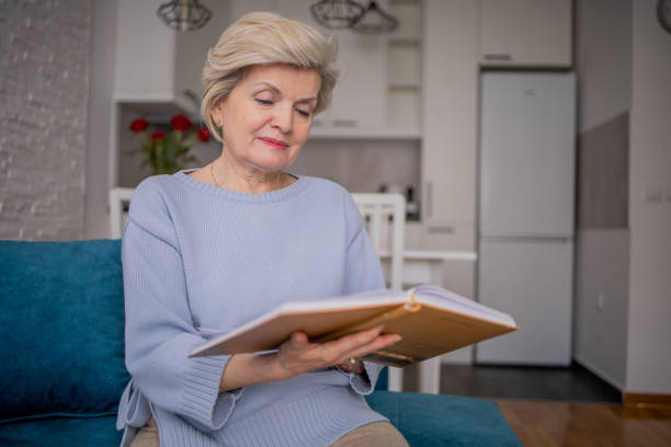istock Senior woman reading book at home 1485089683