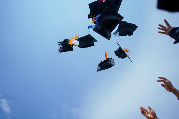 istock Close-up of graduation ceremony university high school graduates throwing cap on the blue sky. 1485090607