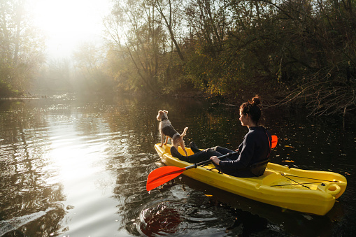 Photo of a young woman kayaking on the river with her dog