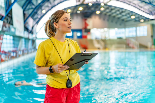 Swimming coach holding a document next to a indoor pool