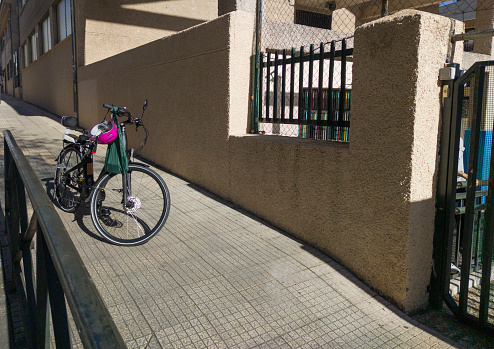 Electric bike parked on the sidewalk, near primary school door. Drop kids off right at school
