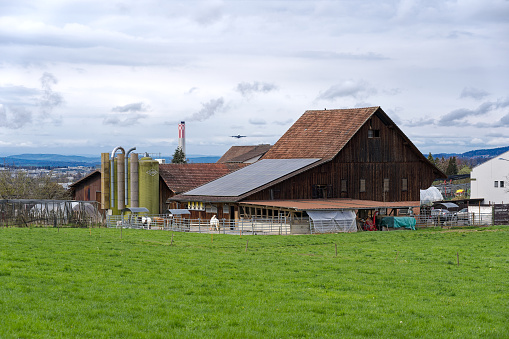 Scenic view of traditional farm house with solar panels on saddle roof at City of Zürich district Schwamendingen on a cloudy spring day. Photo taken April 7th, 2023, Zurich, Switzerland.