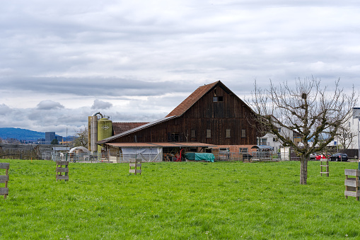 Scenic view of traditional farm house with solar panels on saddle roof at City of Zürich district Schwamendingen on a cloudy spring day. Photo taken April 7th, 2023, Zurich, Switzerland.