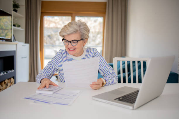 istock Senior woman using calculator while going through bills and home finances 1485099563