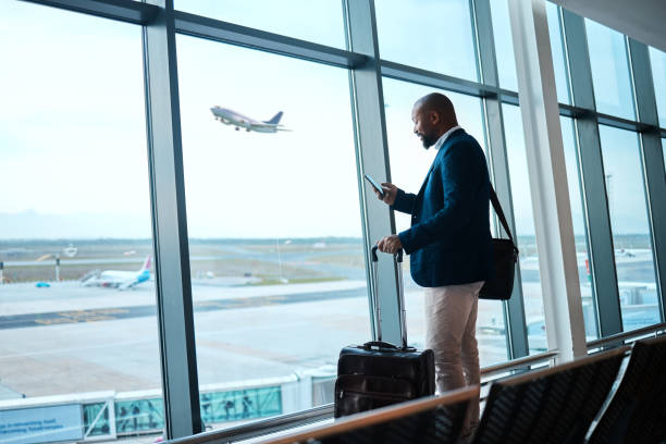 istock Black man with phone, airport window and plane taking off, checking flight schedule terminal for business trip. Technology, travel and businessman reading international travel restrictions app online 1485101408