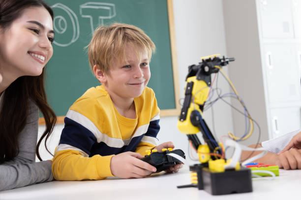 istock Elementary school students are sitting in the classroom at school and playing to robots class 1485107897