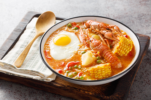 Crayfish soup with tomatoes, corn, pepper, potato and egg close-up in a bowl on the table. Horizontal