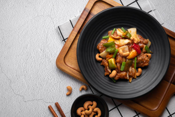 istock Stir fried chicken with cashew nuts in black dish on concrete table. 1485108805