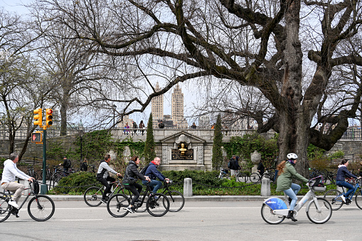New York City, United States, April 7, 2023 - Cyclist in springtime Central Park New York in the background the towers of the San Remo building (by architecture Emerich Roth).