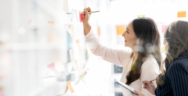 istock young businesswoman creative team using post it notes in glass wall to writing strategy business plan to development grow to success. 1485112681