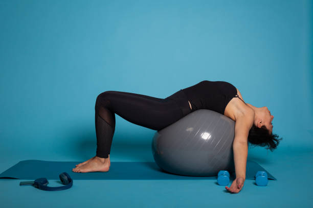 istock Personal trainer woman sitting on pilates fitball practicing abs exercise 1485113712