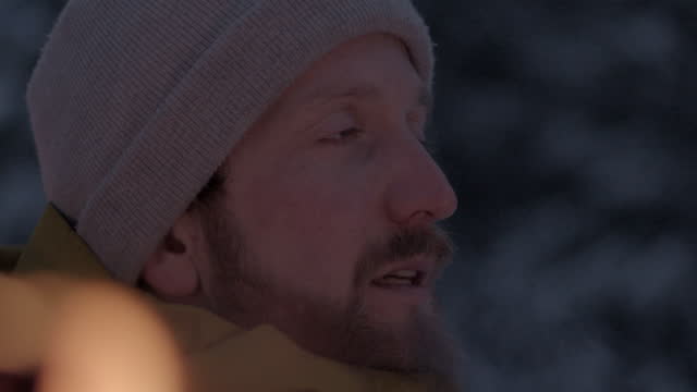 Close up shot of a man with lit torch in a snowy mountain at dusk