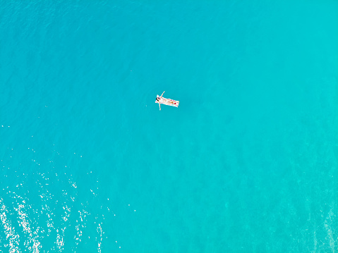 Young woman floating on an inflatable mattress on the sea. Taken with drone.