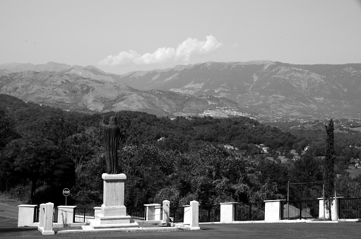 View of statue looking across the mountain in the village of Casalattico, Italy. Statue here is outside the entrance to the cemetary in Casalattico.
