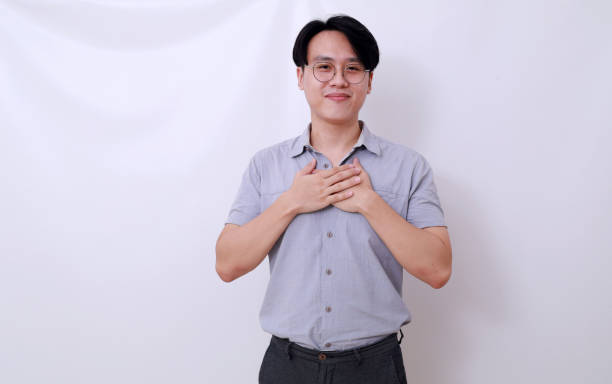 istock Relieved asian man standing while holding his chest. Isolated on white 1485119686