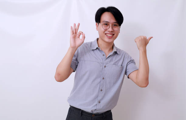 istock Happy asian man showing okay hand gesture while presenting something beside him. Isolated on white 1485119817
