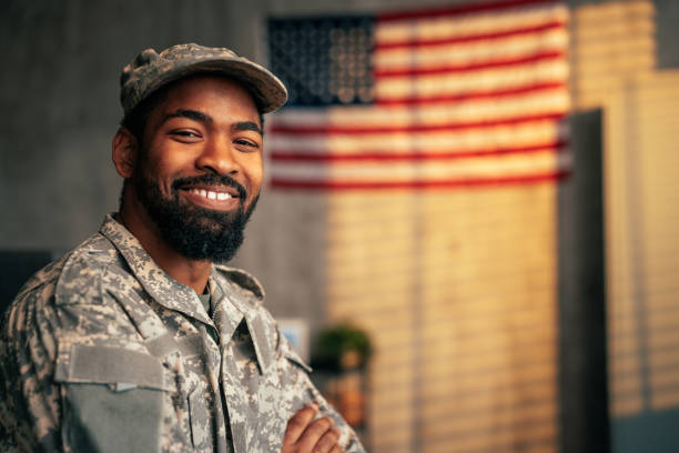 Portrait of cheerful army officer inside. A portrait of a young adult African American army officer inside with the American flag in the background, copy space and looking at camera. police force smiling officer stock pictures, royalty-free photos & images