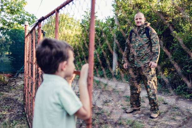 配備から帰国した幼い息子に挨拶するために歩いている興奮した白人の男性兵士。 - embracing smiling gap children only ストックフォトと画像