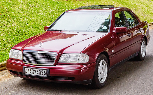 Cape Town, South Africa - February 5, 2023: A well-preserved late-1990s Mercedes-Benz 230K Sport in deep metallic maroon, parked in a street in a wealthy suburb of Cape Town, South Africa.