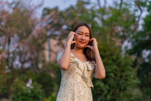 Half body shot of a young beautiful asian woman wandering in a park outdoors during a sunset moment