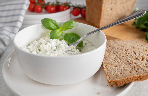 Very healthy meal with cottage cheese marinated with olive oil, and herbs. Served with rye bread on kitchen table. Suitable for heart health, fitness, diet or healthy eating. Closeup and front view