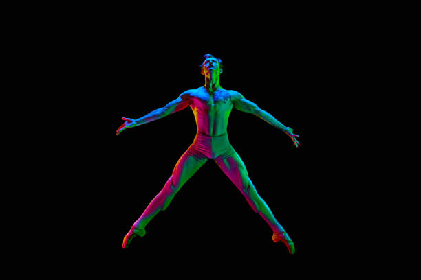 Star pose. Banner with one attractive young male, ballet dancer jumping in air over dark studio background with neon light. Copy space for ad, text. Grace, art, beauty, contemporary dance concept